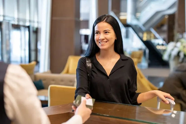 Uśmiechnięta recepcjonistka witająca gościa przy recepcji w hotelowym lobby